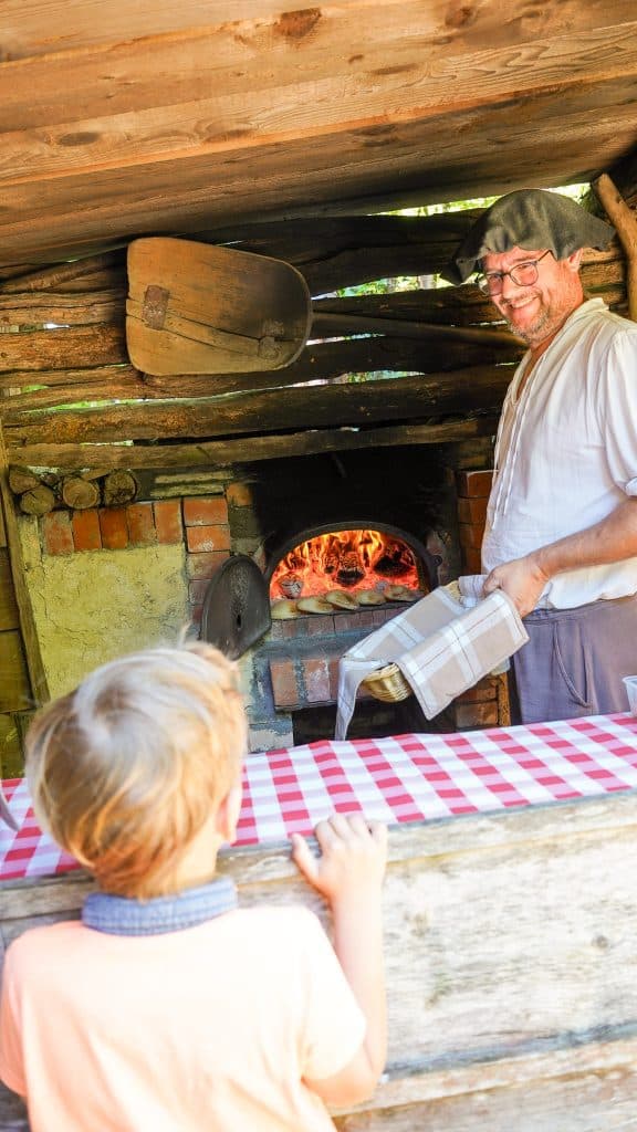 Boulanger préparant des fouées traditionnelles au feu de bois devant des visiteurs à la Vallée Troglodytique des Goupillières